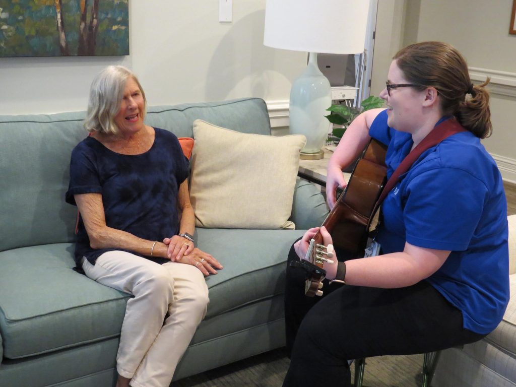 care worker playing guitar for elderly lady