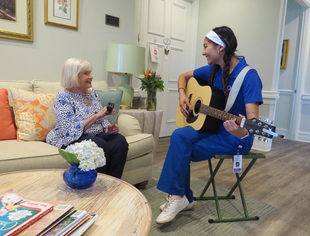 care worker playing guitar for elderly lady